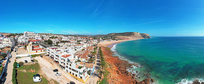 High angle view of sea and buildings against blue sky