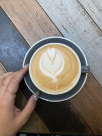 Cropped image of hand holding coffee cup on table