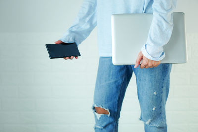 Midsection of woman holding umbrella standing against wall