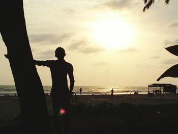 Silhouette man standing on railing against sky at sunset