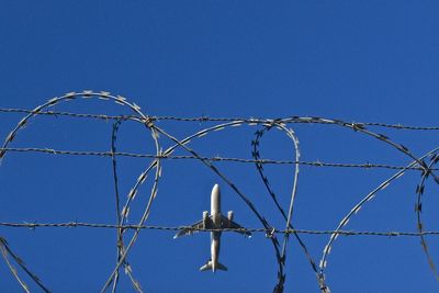 Low angle view of barbed wire against clear blue sky