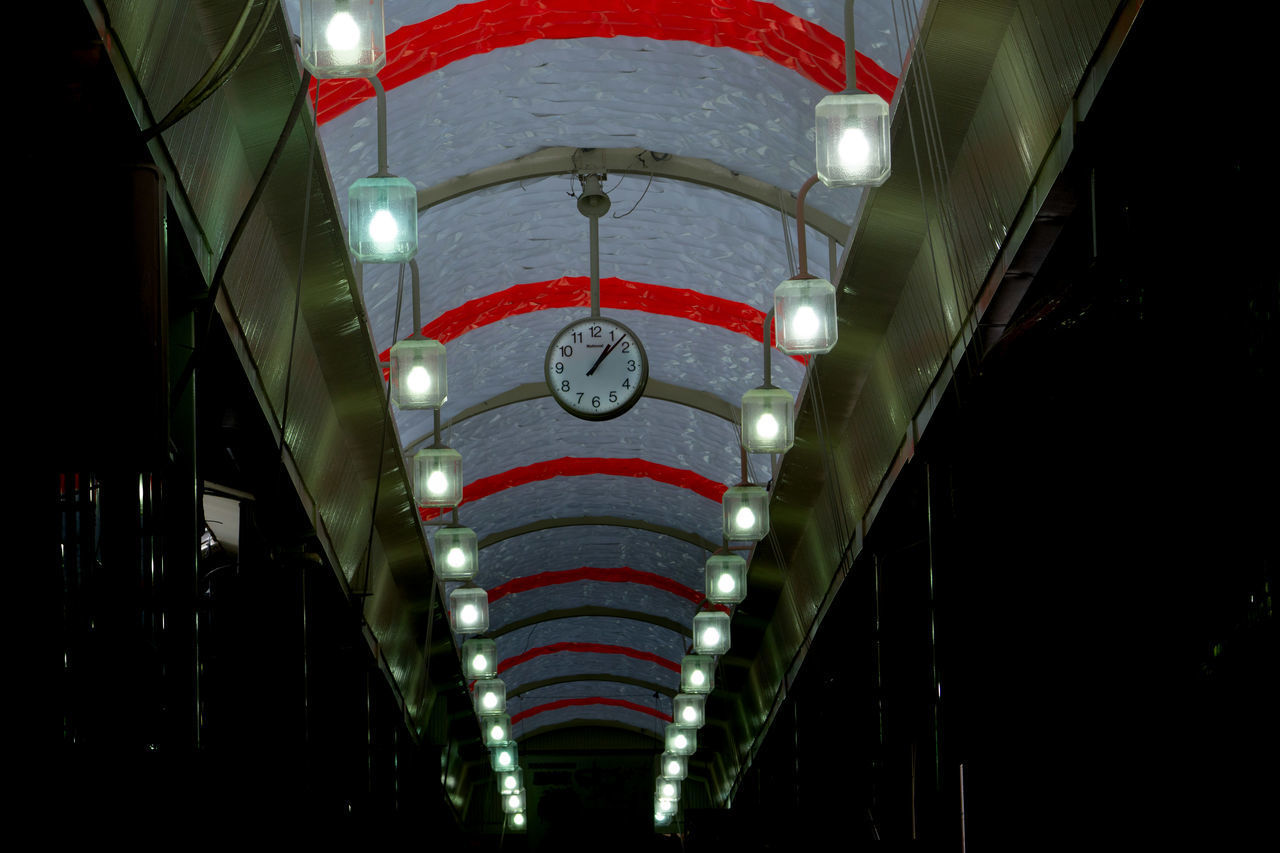 LOW ANGLE VIEW OF ILLUMINATED LIGHTS HANGING ON CEILING AT NIGHT