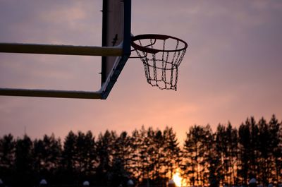 Low angle view of basketball hoop against sky during sunset