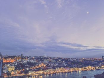 High angle view of illuminated city by river against sky