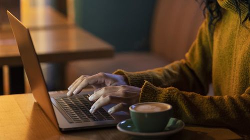 Midsection of woman using laptop at home