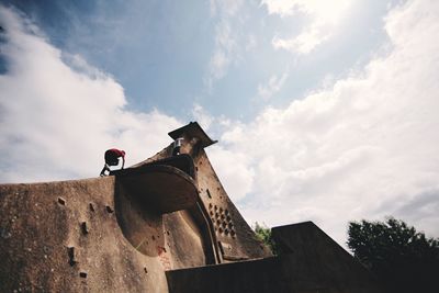 Low angle view of boy standing on metallic structure against sky