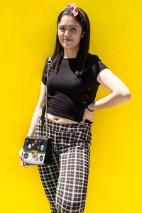 A young latin woman smiling, wearing casual clothes, yellow background