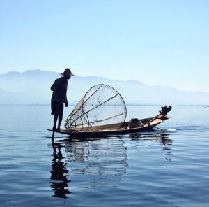 Fisherman with fishing net on boat in lake