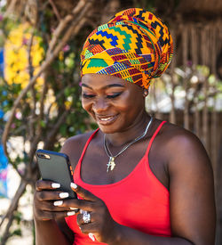 Ghana woman with african colorful headdress standing in the village keta with mobile phone