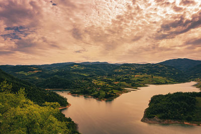 Scenic view of river by mountains against sky