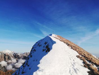 Low angle view of snowcapped mountain against blue sky