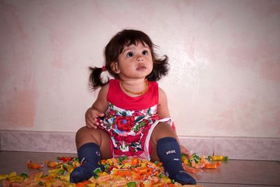 Portrait of cute girl sitting against wall