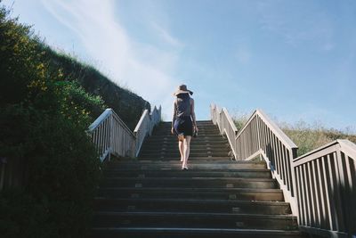 Low angle view of woman on staircase against sky