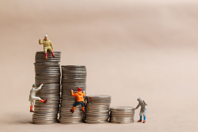 Miniature people mountain climber ascending the coin stack, leadership concept