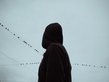 Rear view of man standing against clear sky