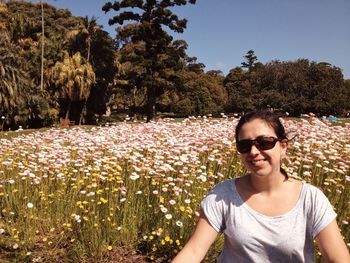 Portrait of smiling woman with sunglasses against trees and plants