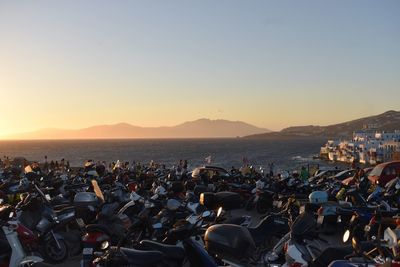 Vehicles parked on sand against sea during sunset