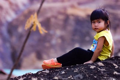 Portrait of cute girl sitting on rock