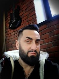 Portrait of young man against brick wall