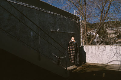 Man standing by tree against building