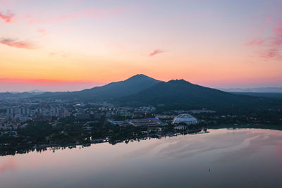 Scenic view of townscape by mountains against sky during sunset