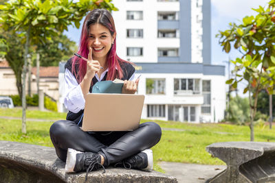 Young woman using phone while sitting on seat