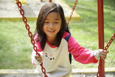 Portrait of smiling girl on swing in playground