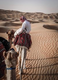 Man standing on sand at desert against clear sky