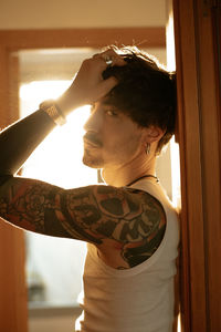 Portrait of young man standing by window