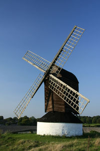 Traditional windmill on field against clear sky