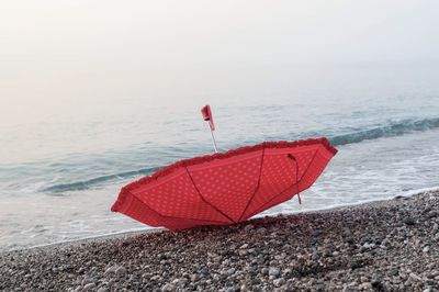 Red umbrella on beach against sky during sunset