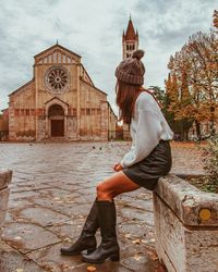 Side view of woman sitting against church in city