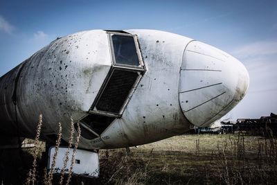 Close-up of abandoned airplane on field against sky