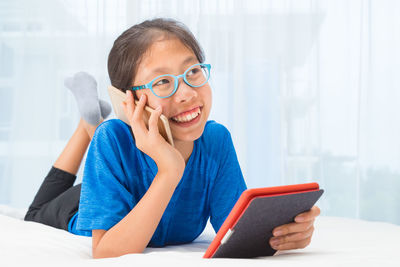 Smiling girl talking on mobile phone at home