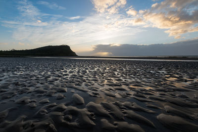 Surface level of beach against sky during sunset