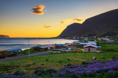 Scenic view of sea by buildings against sky during sunset