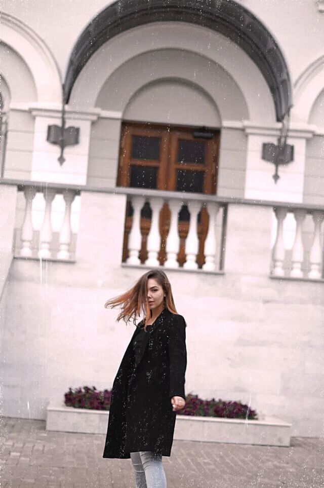 FULL LENGTH PORTRAIT OF WOMAN STANDING AGAINST WALL