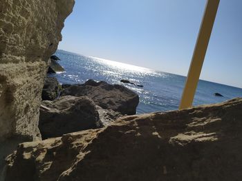 Rocks by sea against clear sky