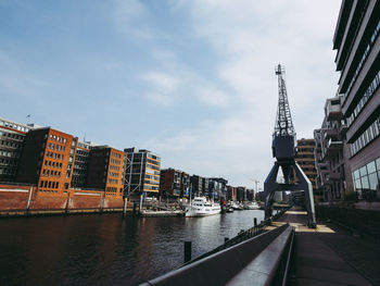 Boats moored at harbor by buildings in city against sky