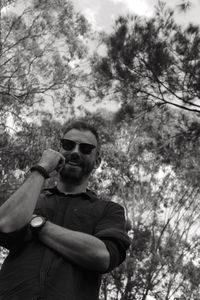 Portrait of young man wearing sunglasses standing against plants