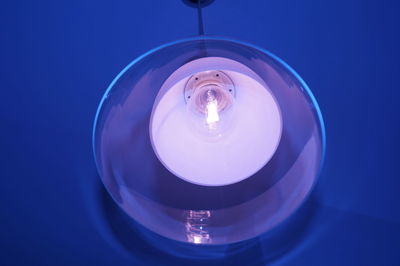Close-up of illuminated light bulb against blue background