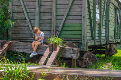 Full length of young woman sitting on old building