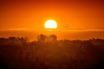 Scenic view of silhouette landscape against orange sky