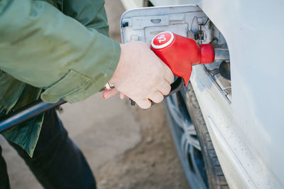 Midsection of man filling fuel in car tank