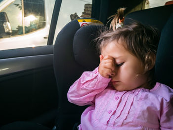 Close-up of cute girl sitting in car