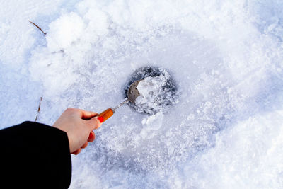 Cropped hand of woman holding snow with spoon