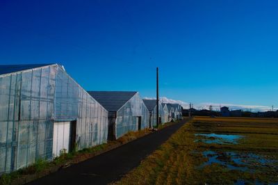 Road amidst buildings against clear blue sky