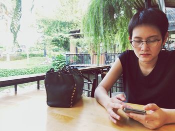 Young woman using mobile phone while sitting on table