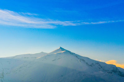 Scenic view of snowcapped mountains against blue sky