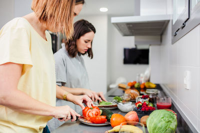 Friends preparing food on kitchen counter at home